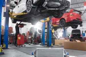 White Subaru STI getting myriad of parts installed on lift