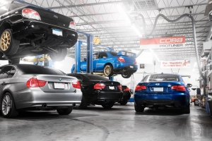 Shop with cars on lifts, three BMW's and two subaru STi